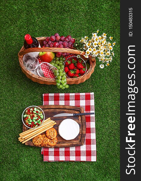 Flat lay composition with picnic basket, wine and products on grass