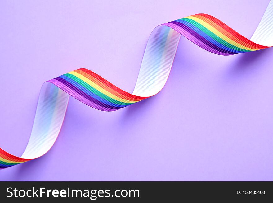 Bright rainbow ribbon on color background, top view. Symbol of gay community