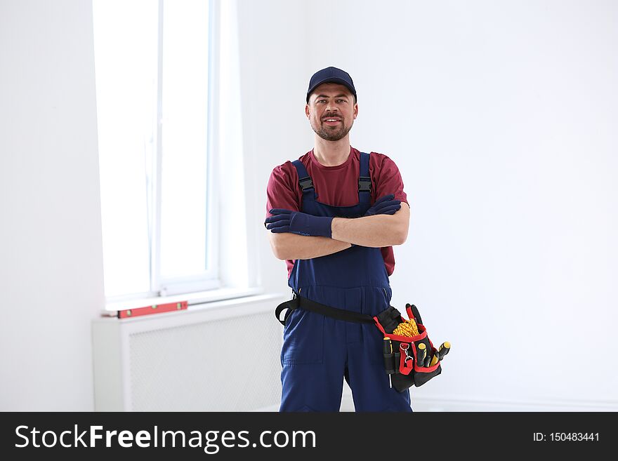 Portrait of professional construction worker with tool belt indoors