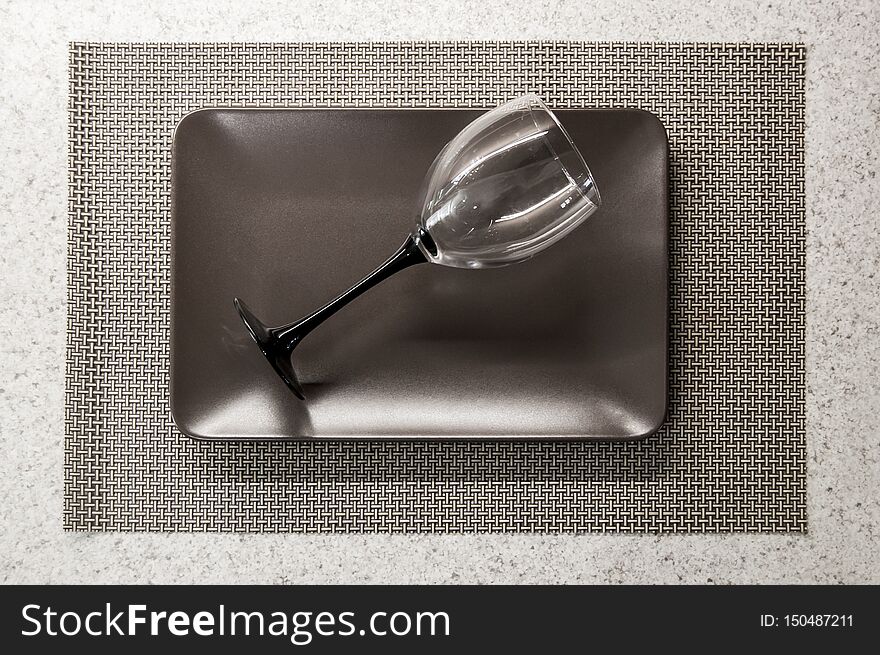 Lying empty wineglass on a brown plate on the tabletop.