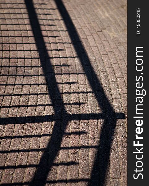 Shadow of a fence falling on brick path