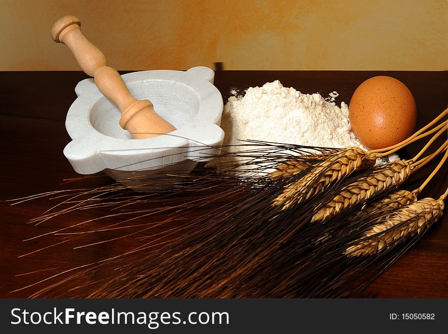 Flour, corn stalks, egg and mortar on wood table. Flour, corn stalks, egg and mortar on wood table