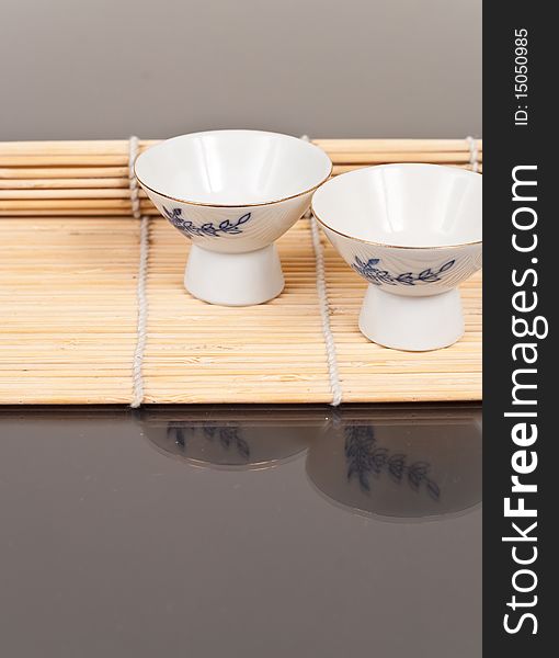 Oriental Alcoholic Sake Cup on a Bamboo Mat. Oriental Alcoholic Sake Cup on a Bamboo Mat