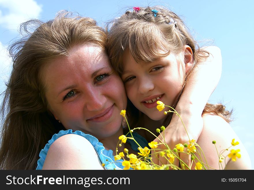 Portrait loving women and girls with yellow flowers in the summer against the sky. Portrait loving women and girls with yellow flowers in the summer against the sky