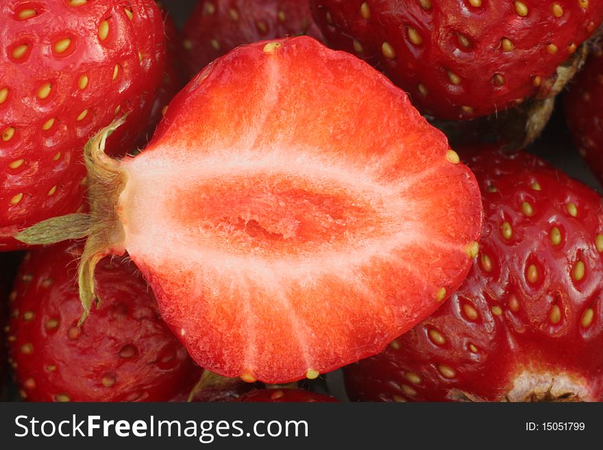 Strawbery slice cut in half with other strawberries in background, macro photograpy. Strawbery slice cut in half with other strawberries in background, macro photograpy.