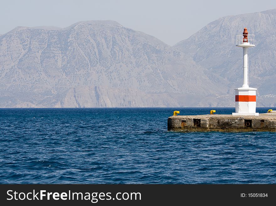 Lighthouse in rocky bay on the island background. Lighthouse in rocky bay on the island background