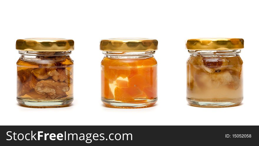 Honey with nuts in a glass jar on white