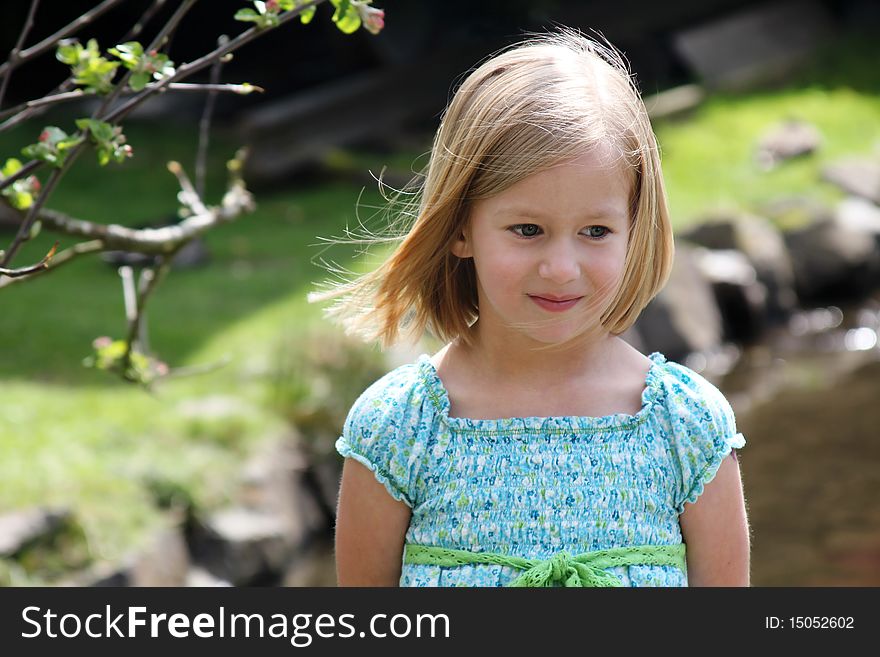 Pretty 5 year old girl in blue dress with light breeze in her hair. Pretty 5 year old girl in blue dress with light breeze in her hair