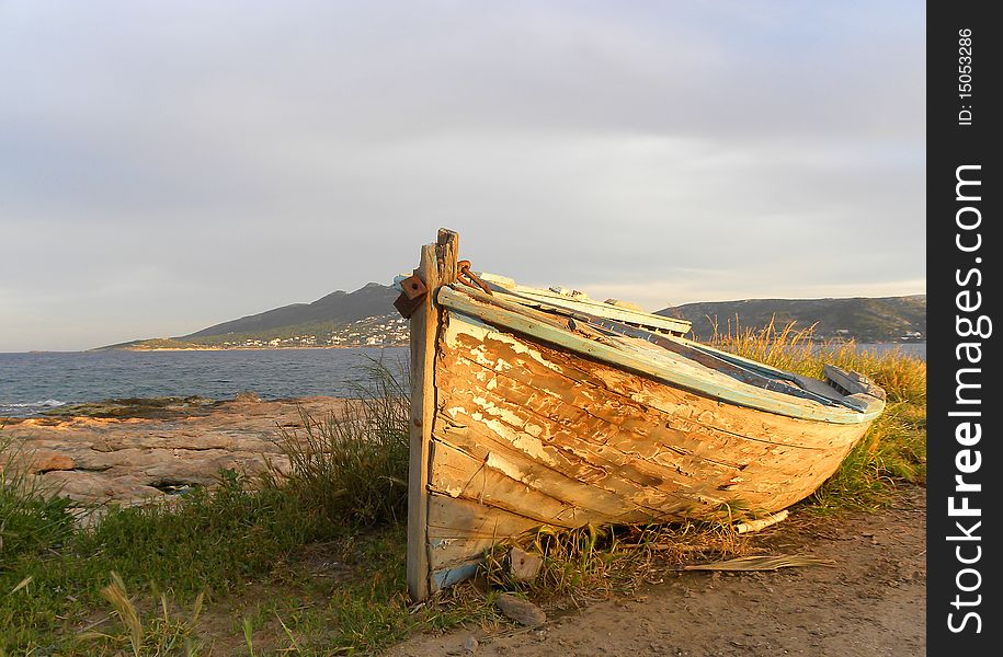 View on the old boat on the beach at sunset. Mediterranean. Greece