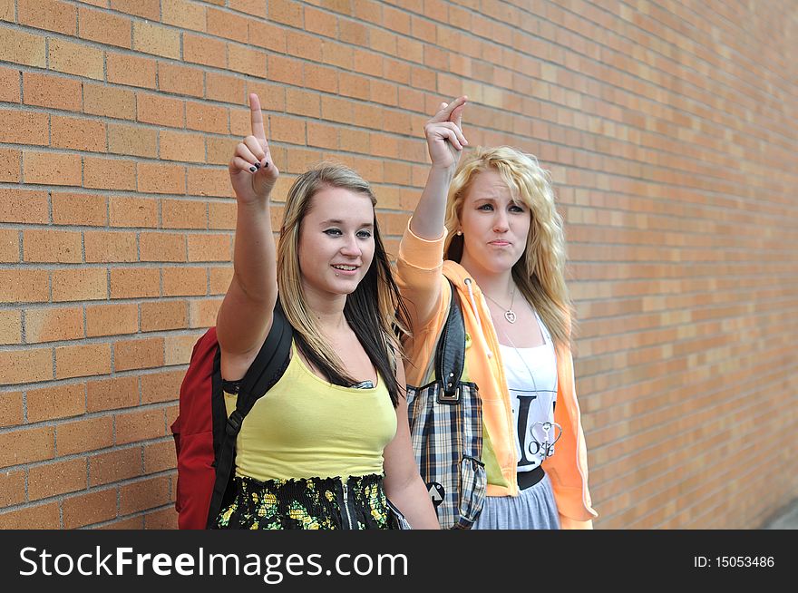 Two teenage girls waving their raised hands and fingers up trying to get a ride. Two teenage girls waving their raised hands and fingers up trying to get a ride.