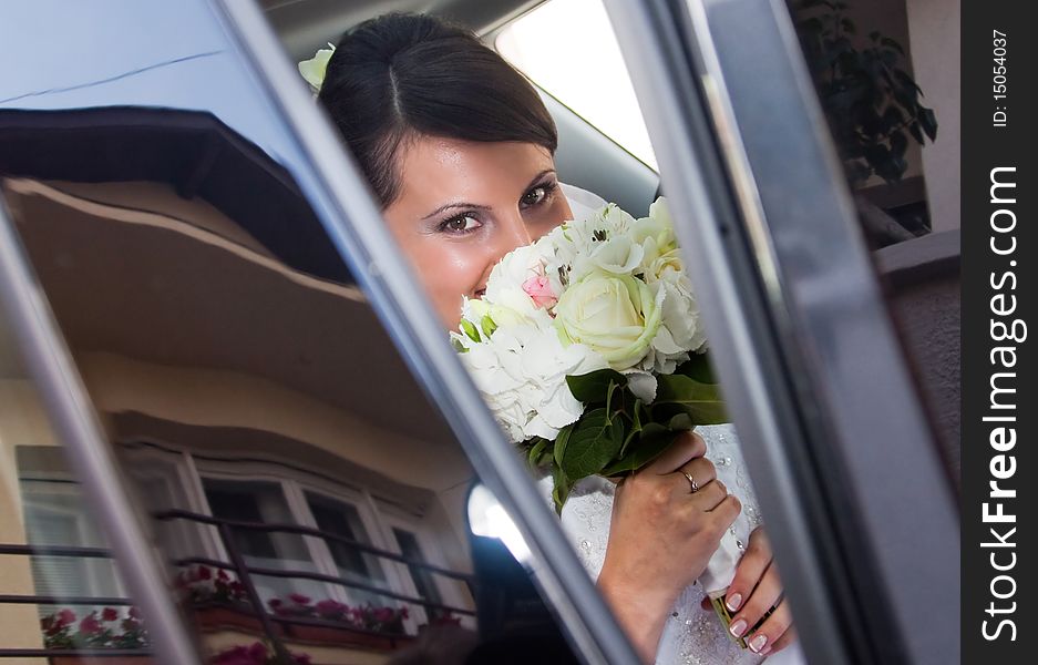 Happy bride with bouquet inside car