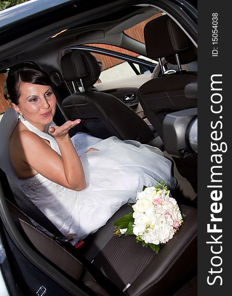 Happy bride with bouquet inside car