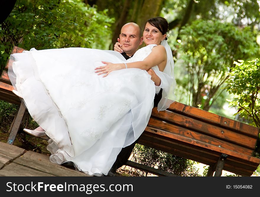 Bride and groom sitting on bench in park