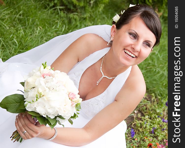 Happy bride with bouquet posing outdoors