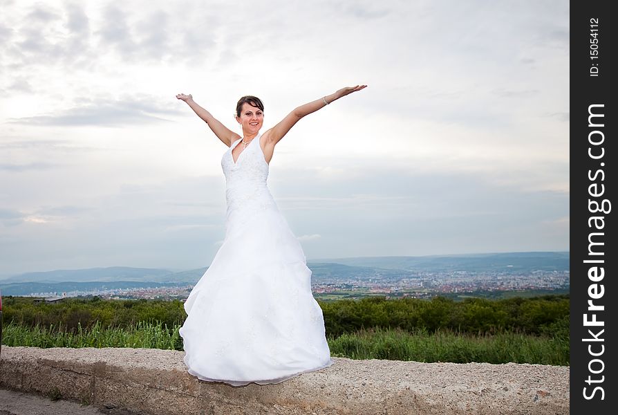 Happy bride with arms wide open against blue sky
