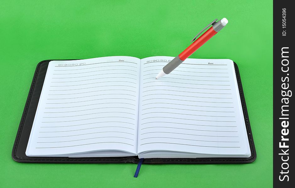 Notebook and pen in the green background