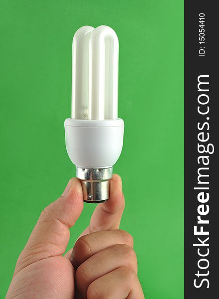 Hand holding energy saving lamp isolated on green background