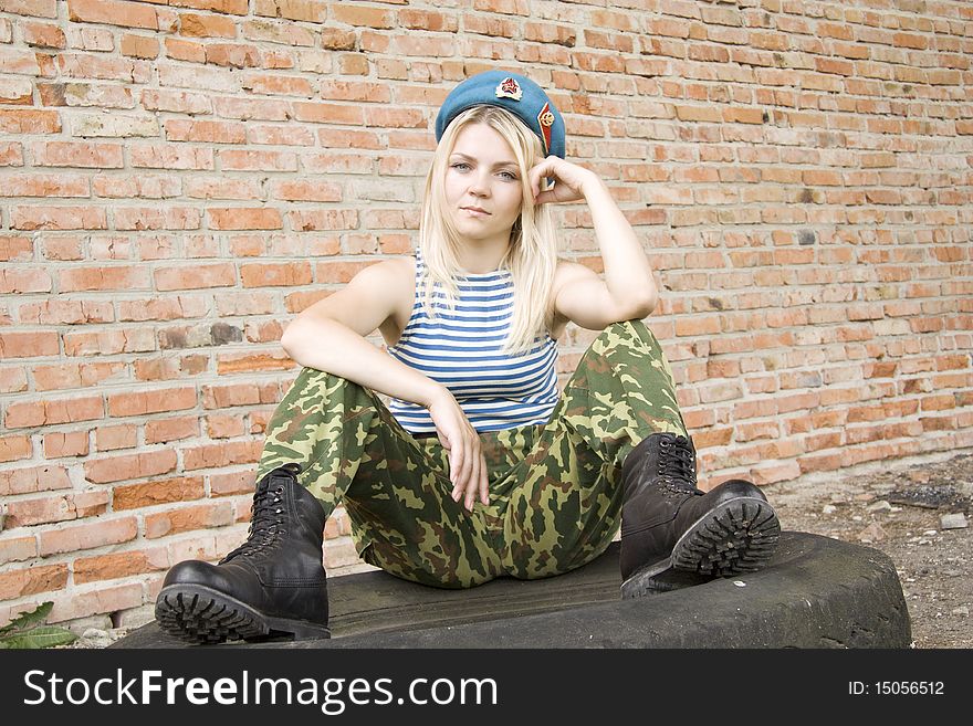 The woman in the military form sits on the tyre and the head is propped up by a hand. The woman in the military form sits on the tyre and the head is propped up by a hand