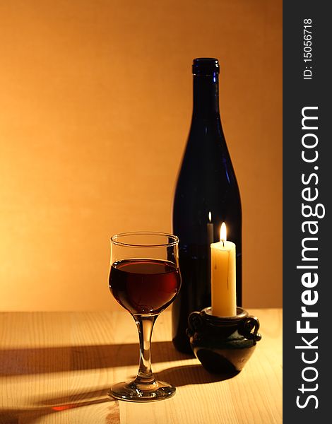 Wineglass near bottle of red wine and candle on nice brown background. Wineglass near bottle of red wine and candle on nice brown background