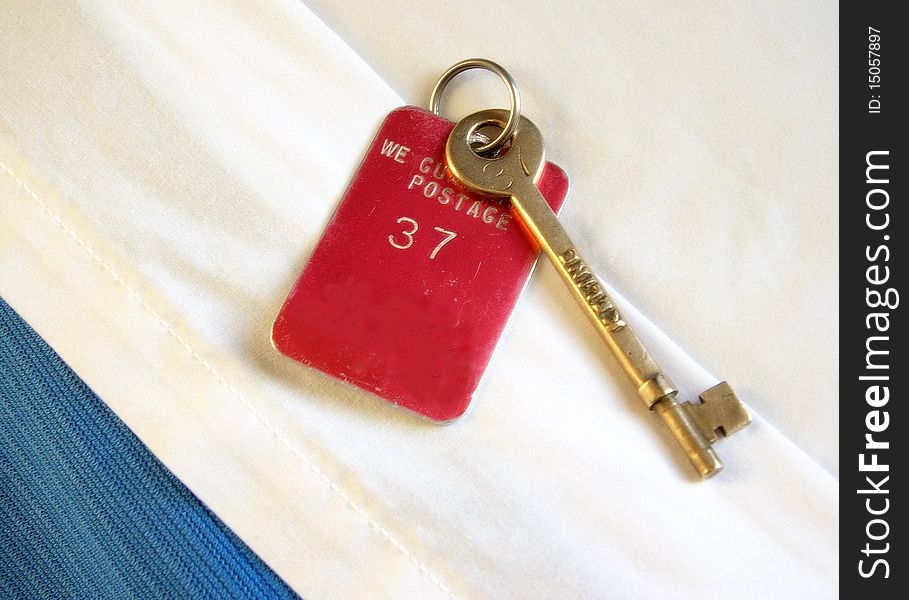 A ships stateroom key resting on the room's turned down sheets of the bed.