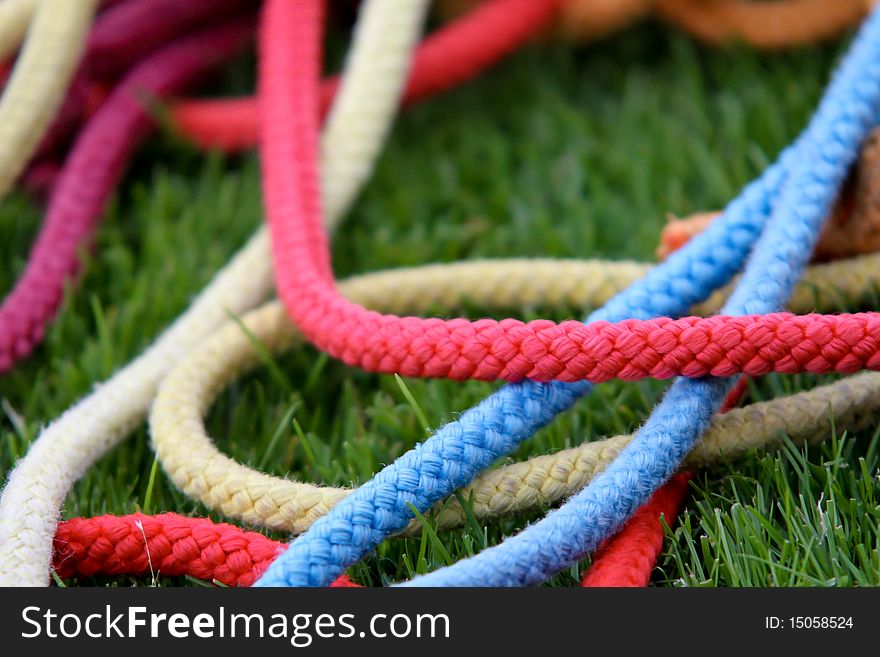 Colorful gymnastics ropes lying in grass. Colorful gymnastics ropes lying in grass