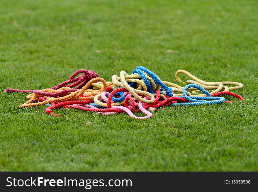 Colorful gymnastics ropes lying in grass. Colorful gymnastics ropes lying in grass