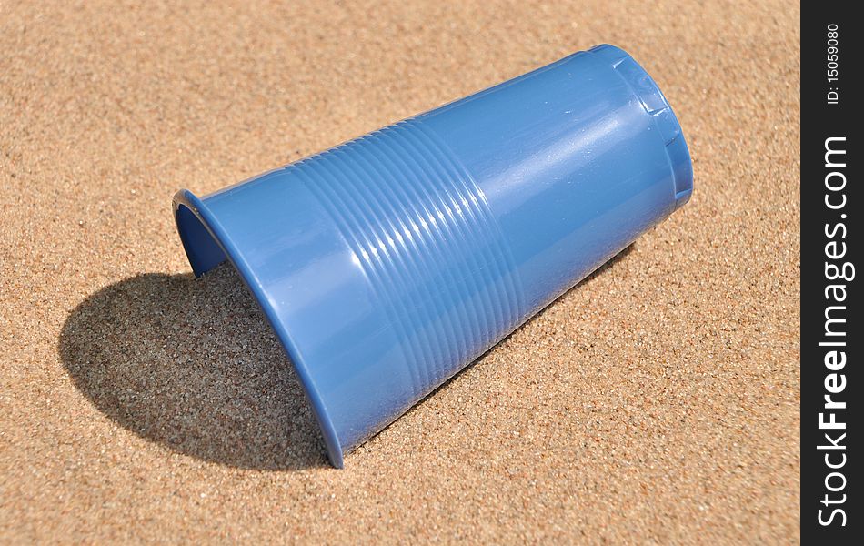 Plastic blue glass on sand. Plastic blue glass on sand.