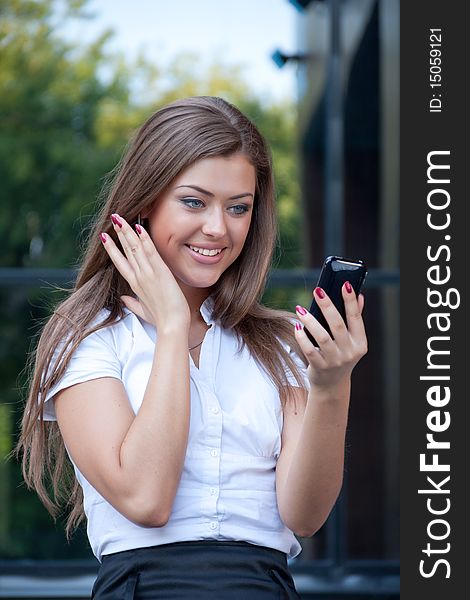 Young woman looks in a cellular telephone and rejoices having seen something on the screen. Business style. Young woman looks in a cellular telephone and rejoices having seen something on the screen. Business style