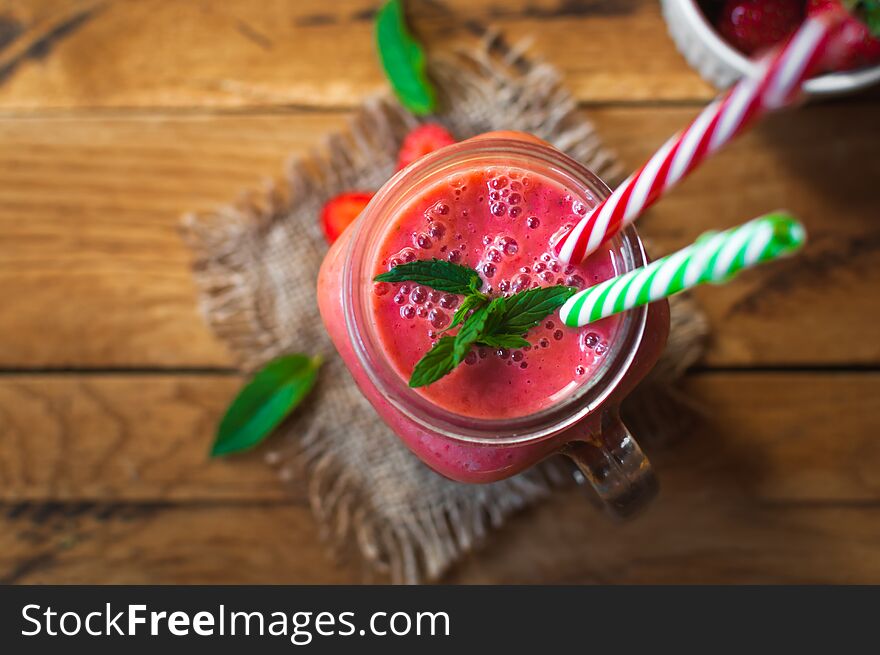 Fresh strawberry smoothie in a glass jar with mint, on wooden background. Fresh strawberry smoothie in a glass jar with mint, on wooden background