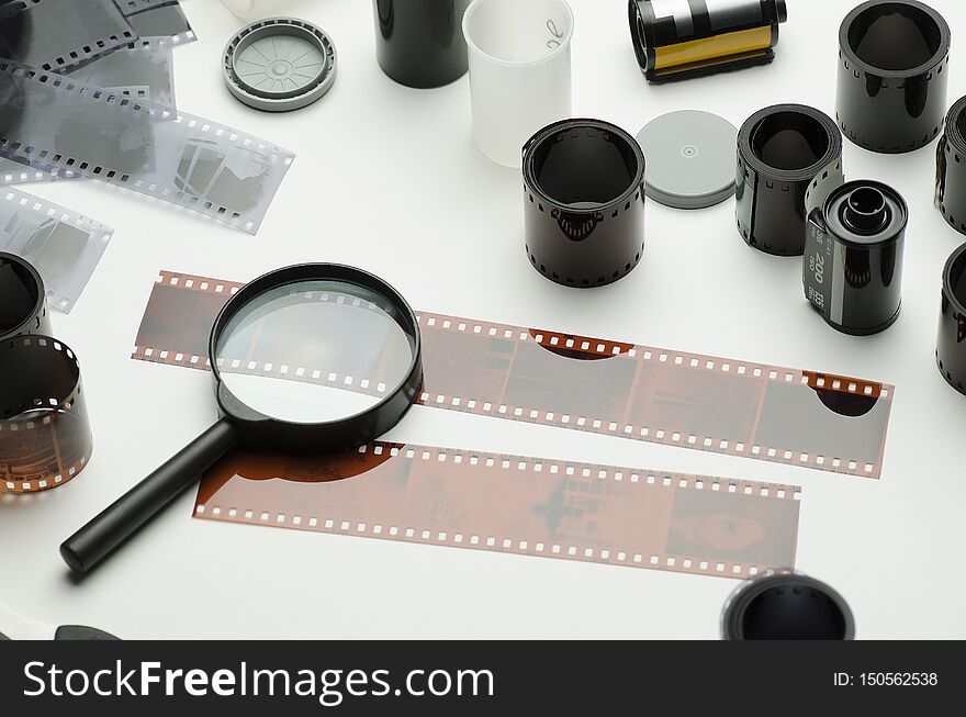 Multiple photographic films, scissors and magnifying glass on white background