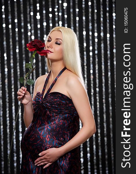 Attractive pregnant woman with red rose