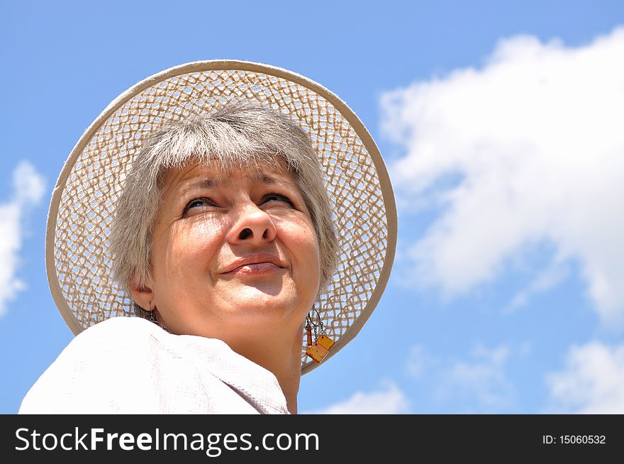 Middle-aged woman in a hat against the sky