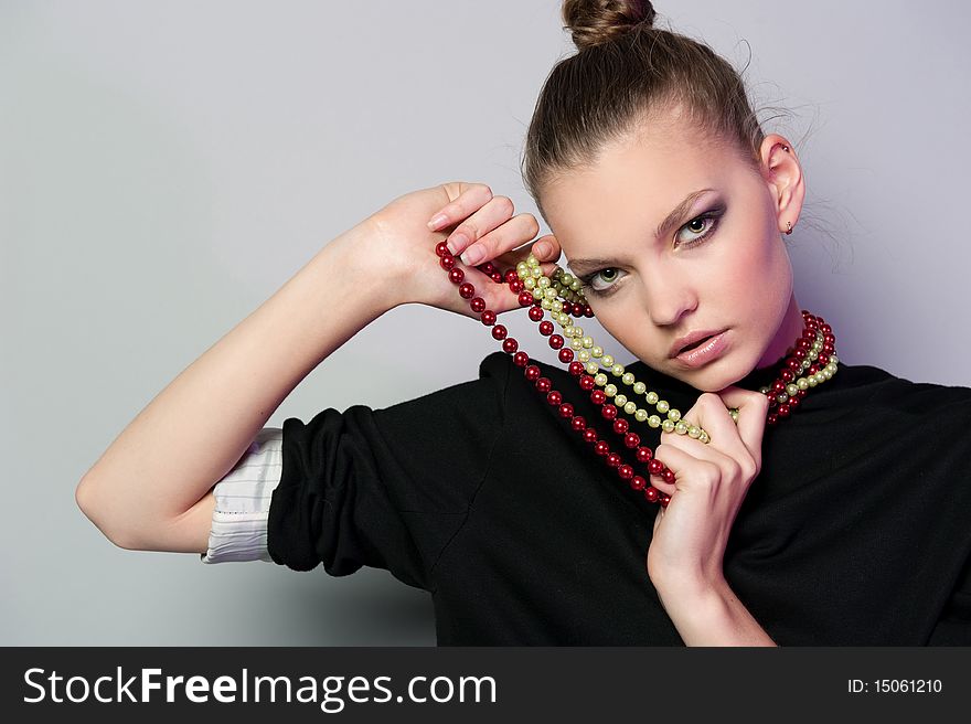 Graceful girl with gray background keeps the beads