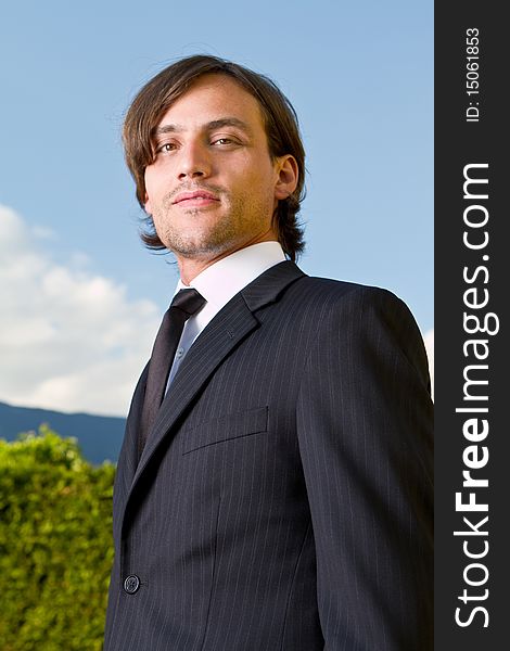Young businessman with longer hair over a blue sky outside. Young businessman with longer hair over a blue sky outside.