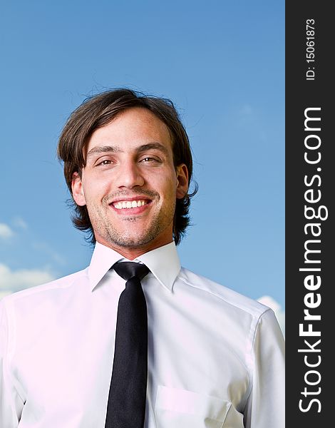 Young businessman with longer hair over a blue sky outside. Young businessman with longer hair over a blue sky outside.