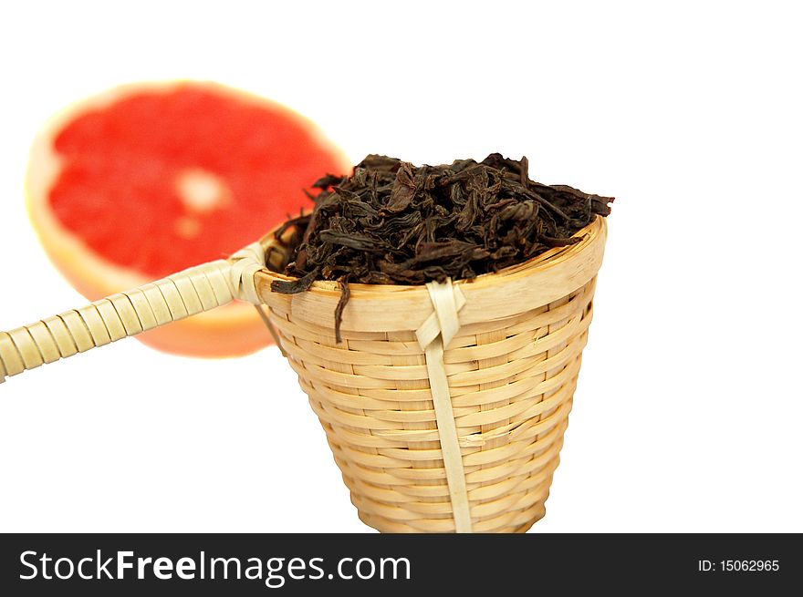 Loose black tea in a wattled basket with a grapefruit isolated  on white background