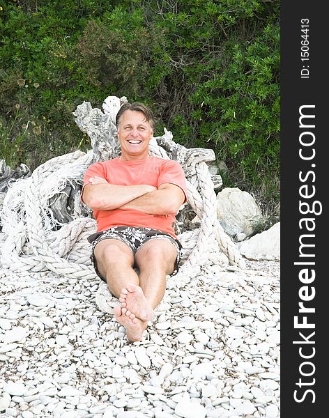 Color portrait photo of a happy forties man sitting on a rocky beach in Greece. Color portrait photo of a happy forties man sitting on a rocky beach in Greece