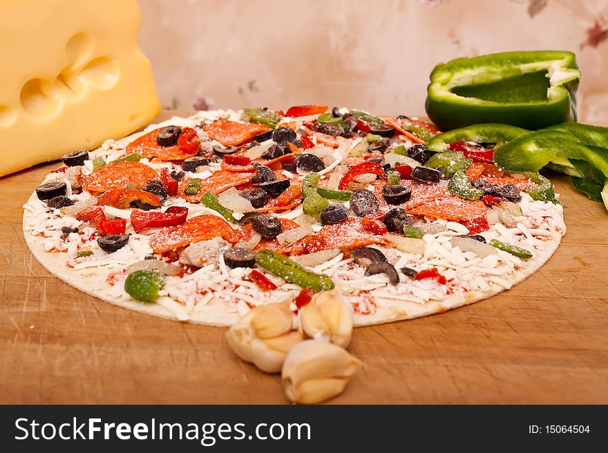 Raw pizza with pepperoni, bell peppers, black olives and onions. Raw pizza with pepperoni, bell peppers, black olives and onions