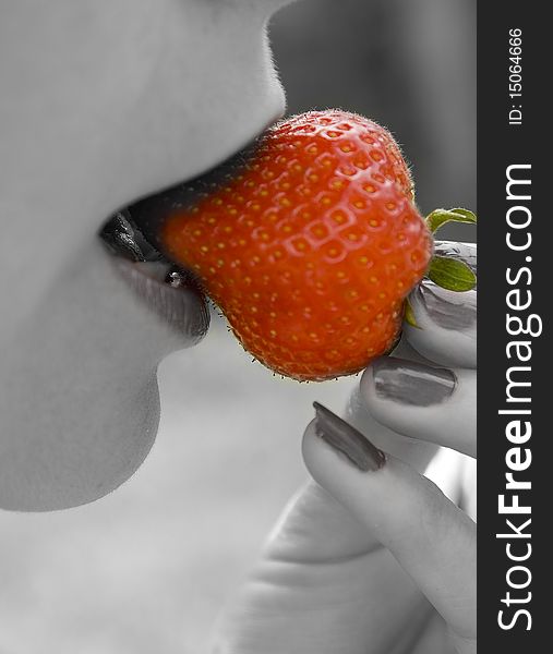 Macro shot of a women biteing into a  large strawberry. Macro shot of a women biteing into a  large strawberry