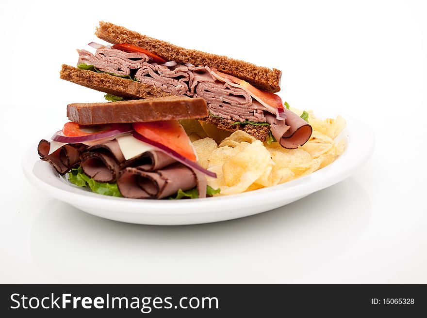 Delicious roast beef sandwich platter with whole wheat bread and potato chips. Delicious roast beef sandwich platter with whole wheat bread and potato chips