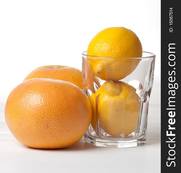 Oranges and lemons in glass on white background