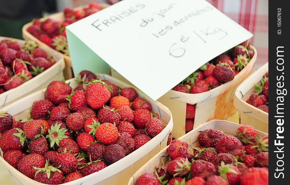 The last strawberries sold in cases on a village market in France. The last strawberries sold in cases on a village market in France