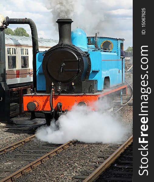 Stream train in yard waiting to take on coal with steam venting from the loco. Stream train in yard waiting to take on coal with steam venting from the loco