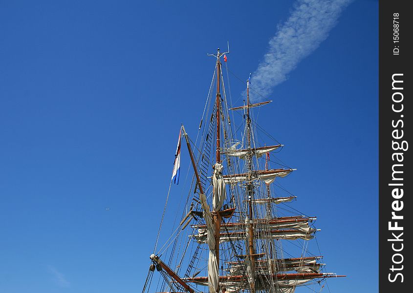 The mast of sailing ship on the background of blue sky