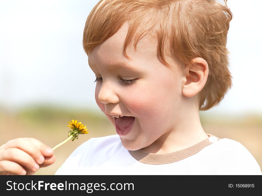 Happy boy enjoy with yellow dandelion on nature