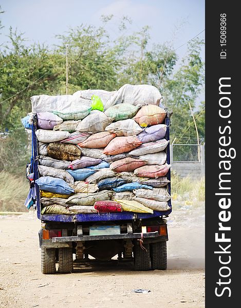 Garbage truck overflowing with trash in old sacks