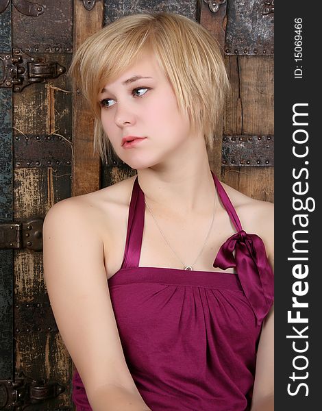 Beautiful blond sitting against an antique trunk with a serious expression. Beautiful blond sitting against an antique trunk with a serious expression