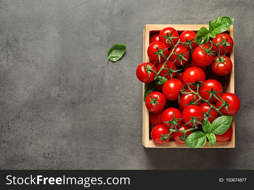 Crate with fresh cherry tomatoes on stone background. Space for text
