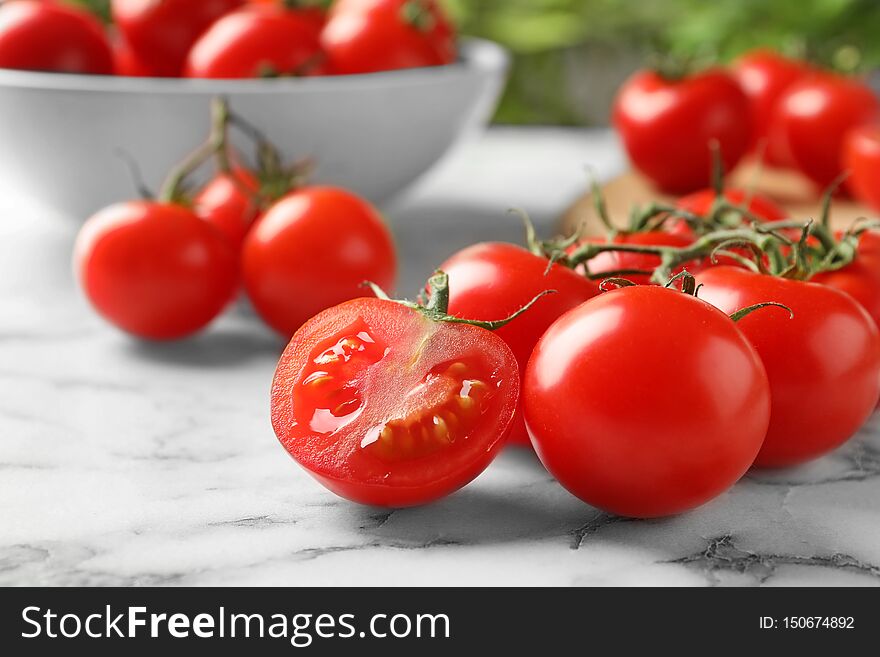 Branch of fresh cherry tomatoes on marble background