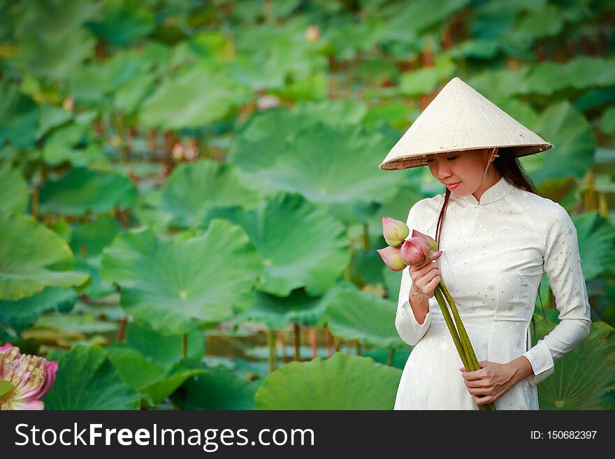 Vietnamese girl wearing a white dress holding a lotus flower. Vietnamese girl wearing a white dress holding a lotus flower